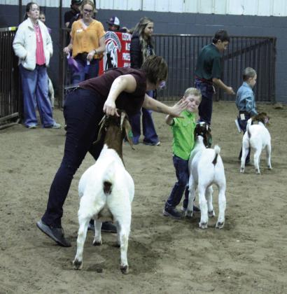 Lane Nagy gets a high five from his mother, Cheryl Nagy, after winning in the Open Meat Goat division of the Pottawatomie County Free Fair Goat Show on Sept. 6. Liam Tooley, far right, took Reserve.