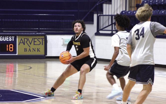 Tecumseh senior Aveon Stokes plans his next move past Shawnee juniors Levi Baughman and Jack Timmons during the basketball scrimmage at Shawnee on Nov. 6.