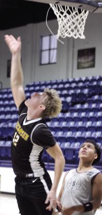 Tecumseh's Jayce Musgrave makes a layup, as Shawnee's Angel Tehauno watches.