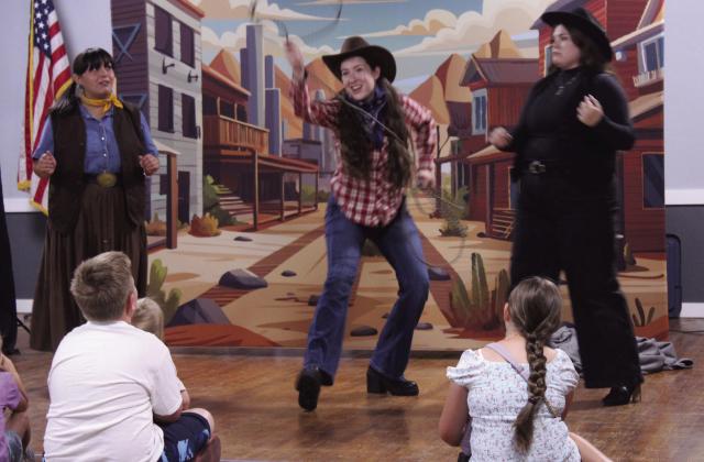 "Pop Magano," played by Savannah Gordon, demonstrates her skill with a lasso, as "Tam," played by Olivia Flores, left, and the "Queen of Knocked Sara Stro," played by Cheyenne Holland, watch during "The Magic Flute Goes West!" Presented by Painted Sky Opera as a McLoud Public Library event, the kid-friendly opera was performed at McLoud's American Legion on July 17. In August, Painted Sky Opera will present Mozart's "The Magic Flute" at the Civic Center in OKC.