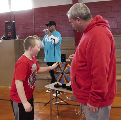 Earlsboro Elementary student Lethanial Hinesley spins the “family” sorting wheel as Principal Stacey Barton watches, Jan. 17. About 90 first- through fifth-graders participated in the positive behavior intervention ceremony where they spun a wheel to choose one of four families, slid down an inflatable slide and got a T-shirt. Each week, the family with the most points for good behavior will receive a reward. Countywide &amp;amp; Sun/Natasha Dunagan