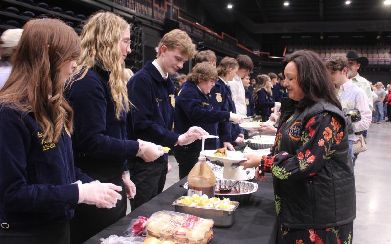 North Rock Creek Chapter Officers, from left, Emma Degman (President), Elexus Helmick (Vice President), and Jase Warren (Treasurer) serve Twana Griffith, of Dale, during the 37th Annual Pottawatomie County Junior Livestock Show (PCJLS) Pig Roast and Trophy Auction, held at FireLake Arena on Feb. 2. Natasha Dunagan, Countywide &amp; Sun