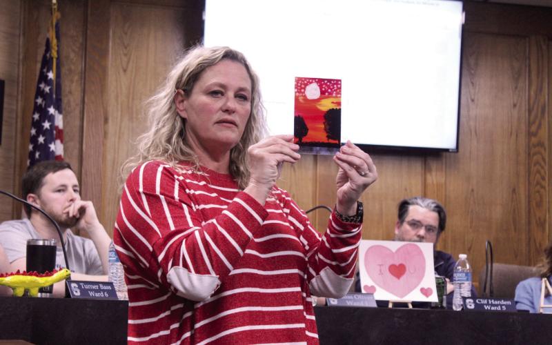 Jefferson Elementary Principal Jennifer Epperley explains one of the six art pieces created by students that she brought to show the Shawnee Board of Education on Feb. 9. The one Epperley is holding is shadow painting on plexiglass. Students from Jefferson also lead the flag salute and moment of silence. Natasha Dunagan, Countywide &amp; Sun