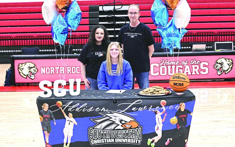 Addisen Lawrence signs with Southwestern Christian University basketball, with her parents Mike and Amber Lawrence. Photo Courtesy of Gowin Photography