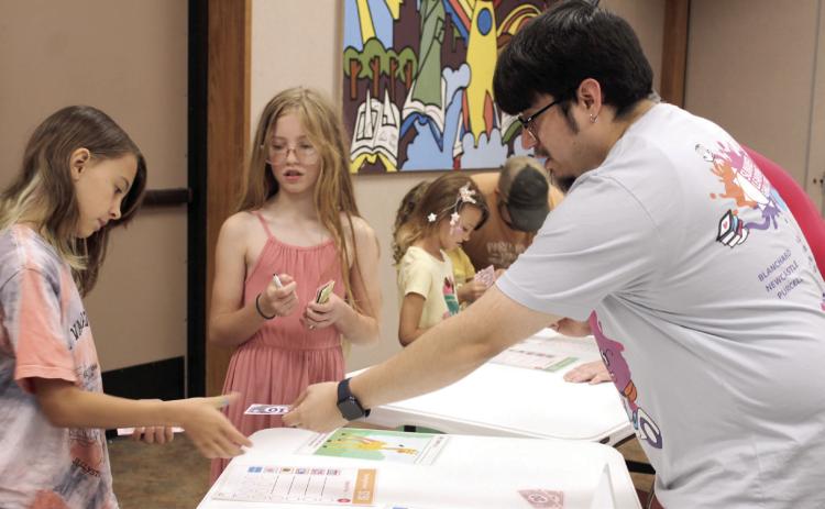 Shawnee Public Library Children's Librarian Jairo Montelongo gives change to Hadley Blake, 10, of Bethel, during the 'Pet Cents' event on June 14. Using play money, Blake bought an ostrich for her pet, and Brylynn Pointer, 11, of Shawnee, bought a giraffe. Montelongo said the library received an American Library Association grant to teach children how to manage finances. Their next event, Making Moo-La, will be on June 21 at 10:30 am.