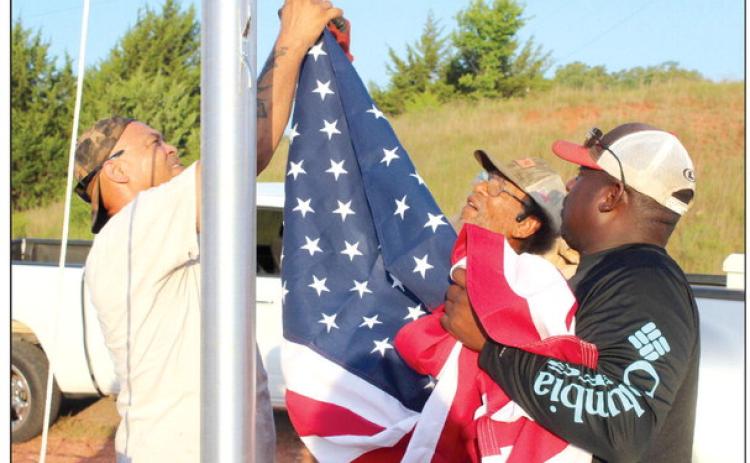 Shawn Edwards, Franklin Edwards and Clarence Bernard attach the U.S. flag to hoist it for the first time on a newly installed 25-foot flagpole at the Brooksville town limits, June 29. Frank Phillips, not shown, said they plan to add lights around the pole, and there will be a “Welcome to Brooksville” sign near it, as well. Countywide & Sun/Natasha Dunagan