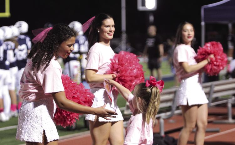 A young girl delivers artwork to two Shawnee High School Pom Squad members, including Michale' Young, during the Oct. 10 Pink Out home game. Also shown are Madison Davis and Rayna Watson. Natasha Dunagan, Countywide &amp; Sun