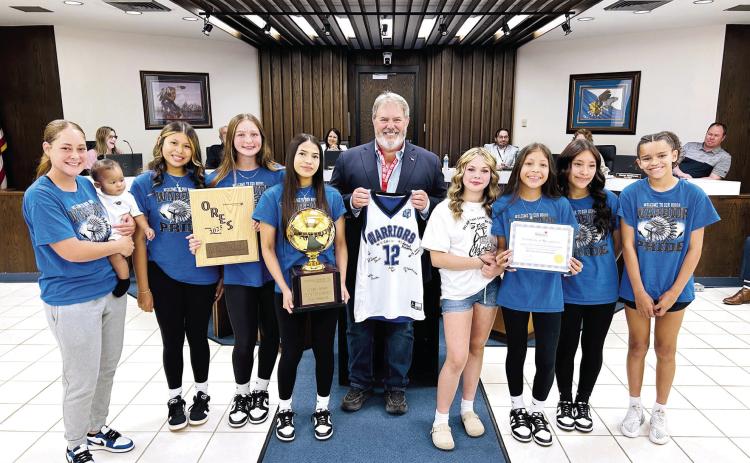 On behalf of the Shawnee Board of City Commissioners, Mayor Eric Stephens presented a Certificate of Recognition to the Pleasant Grove Girls Basketball team who won their second consecutive ORES Division III Championship. The Lady Warriors then presented Stephens with a signed jersey. Shawnee High School Girls Swim Team was also recognized for securing their fourth consecutive OSSAA 5A State Championship title. Both teams received a challenge coin from the Mayor. Photo provided by City of Shawnee
