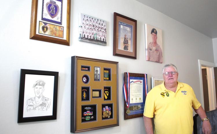 SSG Douglas Warden, of Shawnee, stands by a wall of military mementos, photos, and medals. Warden was inducted into the Oklahoma Military Hall of Fame in October. Countywide &amp; Sun/Natasha Dunagan