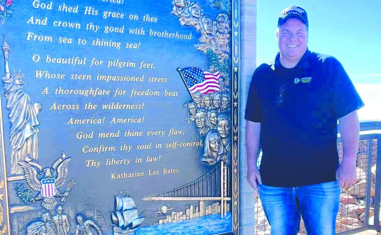 Tecumseh Band Director John Outon poses by the “America the Beautiful” monument at Pike’s Peak in Colorado recently. Outon took his band students on the trip, and they played a concert at the America The Beautiful Park. Photo provided.