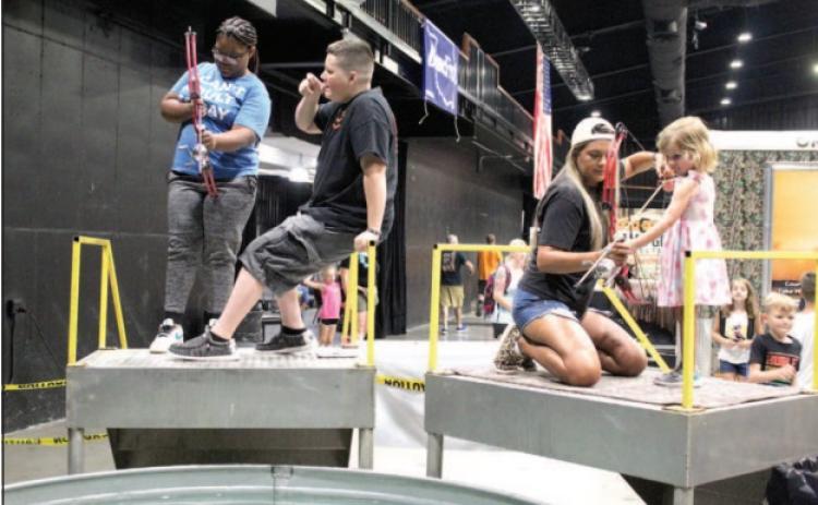 Jadelyn Greer, 15, of Shawnee, and Quinn Jones, 3, of Yukon, get help target bowfishing from Zak McMunn and Jaci Statton, respectively, from Darkwater Adventures of Meeker during the Outdoor Nation Expo on Aug. 13. Countywide & Sun/Natasha Dunagan