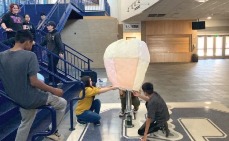 Eliana Rao, Kourgar Simons and Chris Larney launch a tissue paper hot air balloon they created in the Shawnee High School Performing Arts and Activities Center. This was one project done this year in the "Launching Into Aviation" class. Photo provided by Joshua Watson.