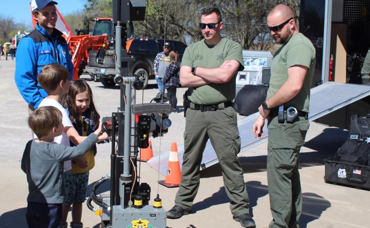 Milo, Julian, and Adelaide Edmison, of Shawnee, get hands-on experience with a bomb-detonating robot, as Deputy Matt Wagner and Sgt. David DeFord tell them about it. The Oklahoma County Sheriff's Bomb Squad robot was a popular attraction during the Touch-A-Truck and Beyond event at the CPN Festival Grounds on April 1. Countywide & Sun/Natasha Dunagan