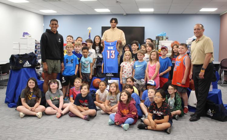 Oklahoma City Thunder Forward Ousmane Dieng, center; Shawnee YMCA Sports Director Brendon Johnson, far left; and YMCA CEO Mike Jobe, far right, pose with about 30 children from the YMCA Summer Camp, being held at Gordon Cooper Technology Center. According to a Thunder press release Thunder, Dieng, through a partnership with Adidas, donated shoes to Shawnee children who were affected by the April 19 tornadoes. YMCA Director of Operations Barbara Boise said 80 summer camp attendees will benefit.