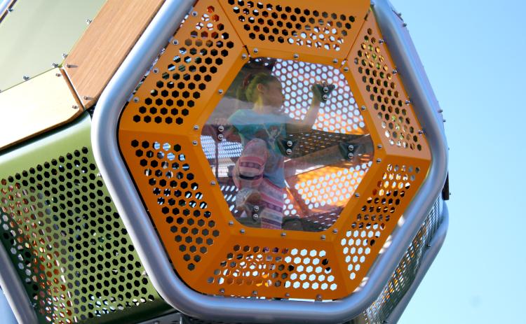 Sarah Esquivel, 5, of Shawnee, looks out a window while climbing inside the largest double-slide equipment during the KidSpace Park Grand Opening on June 23. Countywide & Sun/Natasha Dunagan
