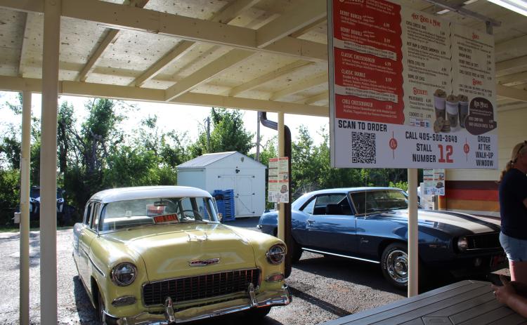 A 1955 Chevrolet Belair, owned by J.R. Lloyd of Shawnee, and a 1969 Chevrolet Camaro, belonging to Shane and Vivian Brown of Shawnee, were two of the vehicles at the monthly Cruise the Poo 2.0 on July 29. They met at The Brown Derby, which reopened on July 26 after recovering from tornado damage. Their original radios could not be replaced, so orders will now be taken using a QR Code, by phone or at the walk-up window, as seen on menus in front of each stall.