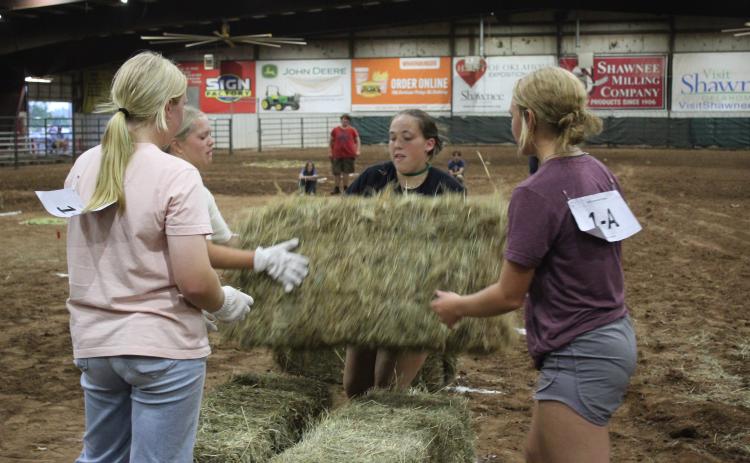 Bethel FFA students Lilly Ingmire, Quinn Carpenter, Bailey Murray and Rianne Tinsley complete their relay race at the Farmhand Olympics by stacking hay bales on Sept. 6. Countywide & Sun/Natasha Dunagan