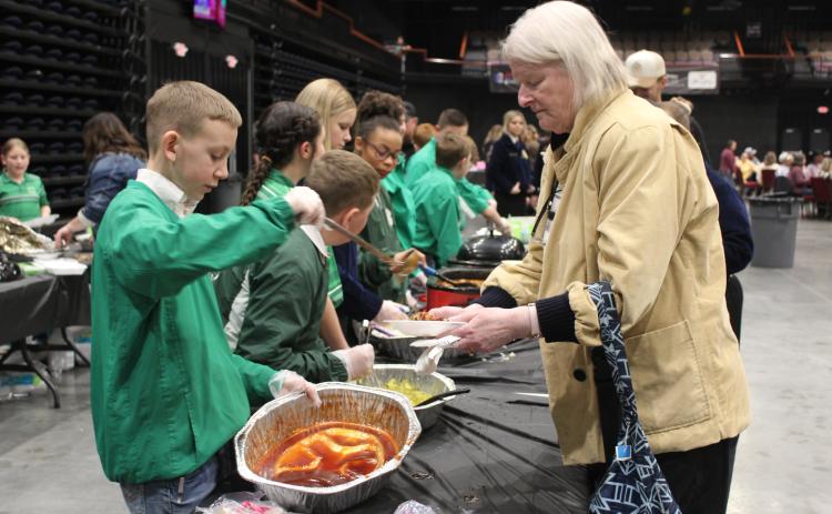 Tecumseh 4-H member Preston Haines adds barbecue sauce to Martha Golleher's plate during the 35th Annual PCJLS Pig Roast and Trophy Auction on Feb. 5 at FireLake Arena. The event brought in $60,000 this year. Countywide & Sun/Natasha Dunagan