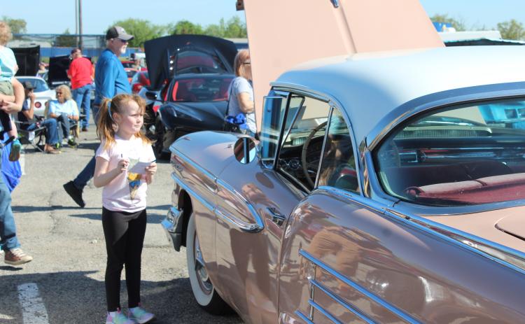 Brynley Stroud, 6, of McLoud, takes down the information from a 1958 Oldsmobile Holiday Coupe, belonging to Gayla Hays, so she can vote for it to receive the Kids Choice Award. The pink and white coupe was one of 136 vehicles in the Eighth Annual Bethel Band Boosters Car Show Fundraiser on April 13. Countywide & Sun/Natasha Dunagan