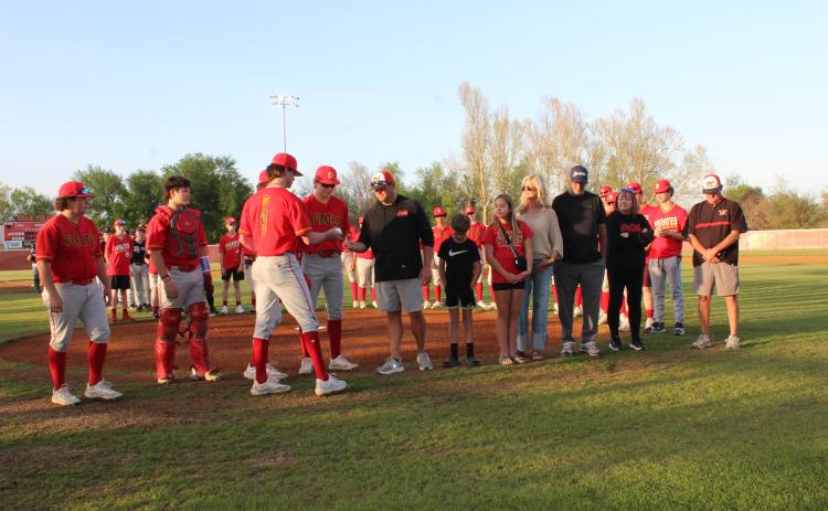 Dale senior Cade Dickinson and his fellow seniors present a commemorative game ball and Dale Pirates hat to 2001 graduate Eric Thornton during a special presentation on April 8 before the varsity baseball game.