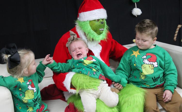 Millie Mullings, age one, is not happy sitting on the Grinch's lap, even with the support of her siblings, Kate Mullings, 3, and Koe Mullings, 5, at Grinchmas in Tecumseh on Dec. 5. Free pictures with the Grinch were offered by the Tecumseh Public Library in the City of Tecumseh Chambers, while Selfies with Santa were available on the auditorium stage. Countywide & Sun/Natasha Dunagan