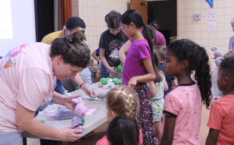 After hot gluing on the eyes, nose and tail and separating the ears, Tecumseh Head Librarian Beth Lyle shows a girl her 'Muttigree' buddy during the Jasmine Moran Children's Museum event at the library on July 17.