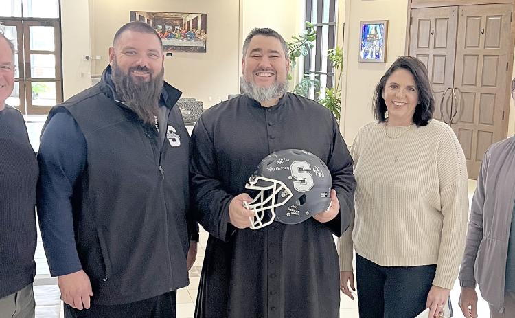 On Dec. 5, Shawnee Wolves Football Head Coach Jason Madonna presented St. Benedict's Church Very Rev. Christopher Brashears, pastor, and Danielle Roberts, office manager, with a helmet autographed by the football team players. See full cutline below.