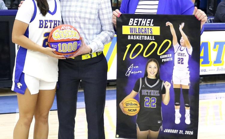 Bethel senior Ava Gascon achieved her 1,000th point at the Jan. 21 game. Shown here, on Feb. 10, Coach Tara Satterfield presents a game ball and Athletic Director Jennifer Lynch holds a banner for Gascon. Photo Provided