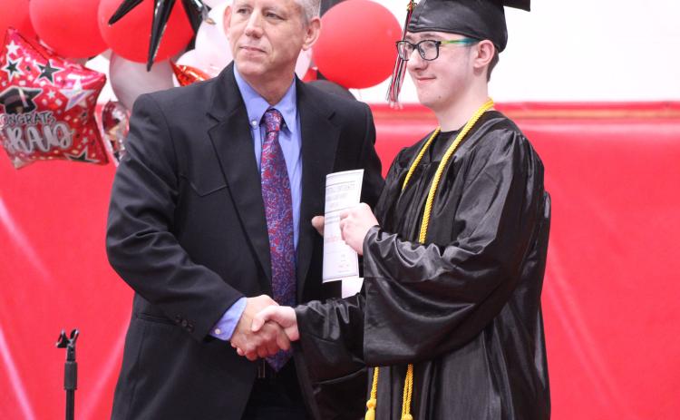 Macomb High School Principal Steve Martin presents an academic scholarship award from East Central University to graduate Jasson Harris-Green during Macomb's Graduation on May 9. Harris-Green was the Salutatorian this year, but Martin spoke about his accomplishments in his place, as Harris-Green chose not to speak. Natasha Dunagan, Countywide & Sun