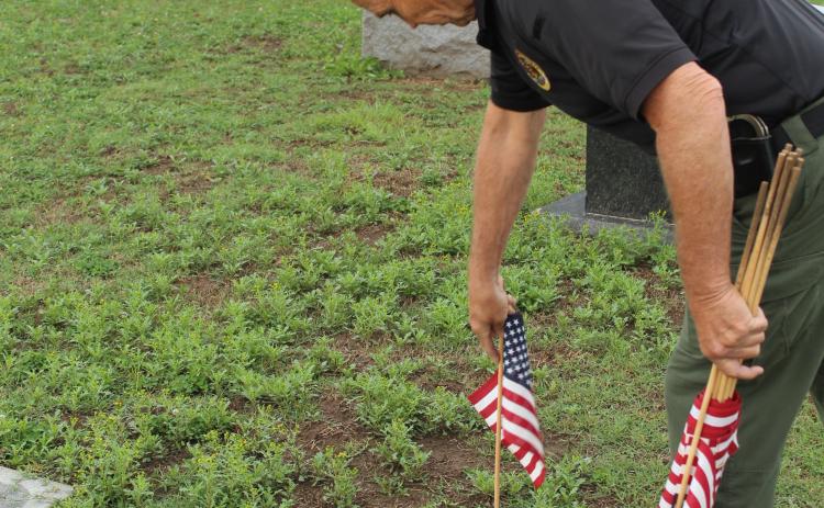 Pottawatomie County Sheriff Freeland Wood decorates the grave of Army Staff Sergeant Robert Sanders, who was in WWII, at Fairview Cemetery in Shawnee on May 23. Wood's son, Justin, and grandson, Everett Wood, 13, also helped to place flags, as they have for a few years, before Memorial Day. Photos by Natasha Dunagan, Countywide & Sun