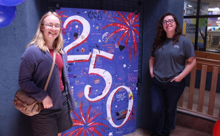 Oklahoma Baptist University graduates Linnea Malmberg, left, and Abigail Ryan pose by a community tile artwork, which they coordinated since May, during the "Pop In to Celebrate America's 250th Birthday with Popcorn and Ice Cream" event at Shawnee Public Library on June 29.  - Photos by Natasha Dunagan, Countywide & Sun