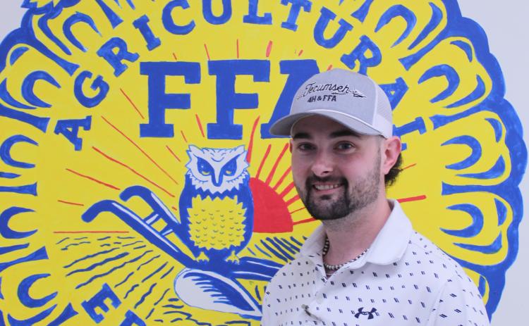 Chase Ferguson poses by the FFA logo that he and his students painted in his classroom at the THS Ag Building.  Photo by Natasha Dunagan, Countywide & Sun
