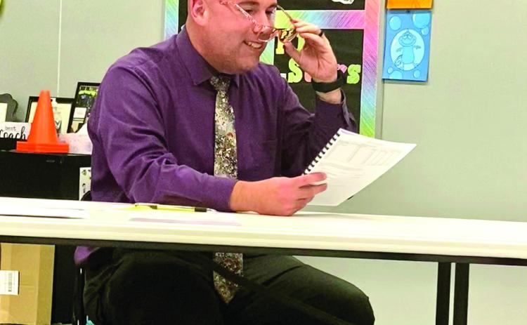 Superintendent Robert Kinsey, with a giggle, borrowed some glasses to read the fine print on the Estimate of Needs document being voted on by the board Sept. 8. Julie Talton, Countywide &amp; Sun