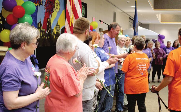 Fellow cancer survivors applaud after Rex Higgins spoke during the Relay for Life, held at the Heart of Oklahoma Conference Center on May 6. Committee Co-Chair Harriet Byers passed along the microphone and handed out carnations to the survivors. At far left, Linda Brown has dealt with six cancer diagnosis in the past 38 years and has been involved in the event since 1989.