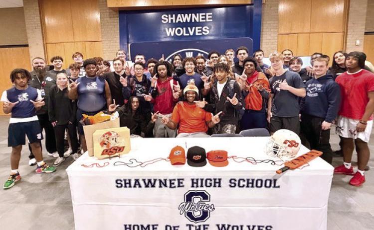 The Shawnee Wolves football team surrounds Ja’Qwon Evans, pistols firing, in celebration of his signing with OSU. Photos Provided