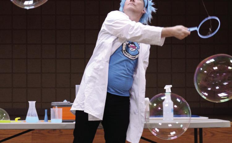 Professor Bucket, aka Joe Coover, with Funky Monkey Magic demonstrates how to make large bubbles, with the help of guar gum and spraying mist in the air, during the 'Bubble Party' at Tecumseh Public Library on July 31. Natasha Dunagan, Countywide &amp; Sun