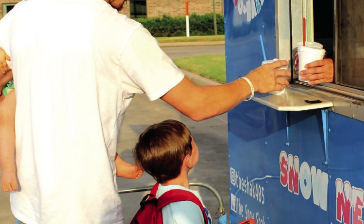 A family gets their free snow cones from The Snow Shak during the Sixth Annual Shawnee BancFirst Back to School Bash on Aug. 6. In addition to free snow cones, BancFirst gave away free hot dogs and backpacks full of school supplies. Shannon Chandler, BancFirst Regional Sales and Marketing Coordinator, said they had between 100 to 150 people attend the Shawnee event and around 100 in total at the Tecumseh and Mc-Loud events this year. Natasha Dunagan, Countywide &amp; Sun