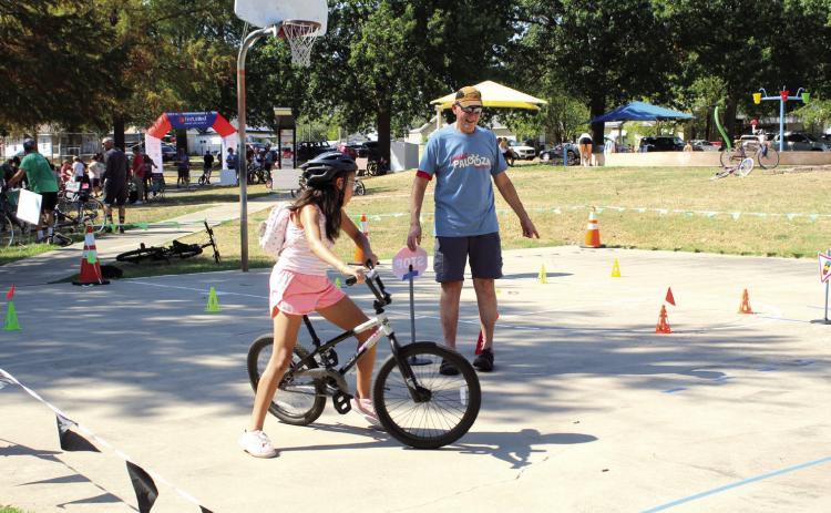Pottawatomie Go (POGO) volunteer Craig Walker directs M'Chylah Walker, 11, where to go on the bicycle obstacle course. Photos by Natasha Dunagan, Countywide & Sun