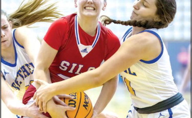 Pictured left, Bethel sophomore Josie Megehee, far left, and senior Hannah Davidson, far right, fight to take control of the ball from a Silo player in the Class 3A Area game, played at Jenks on March 3. The Lady Wildcats won, 60-54, and will compete in the State Tournament today (March 9), 4:30 pm at the State Fairgrounds Arena. Photo provided by Richelle Treece.