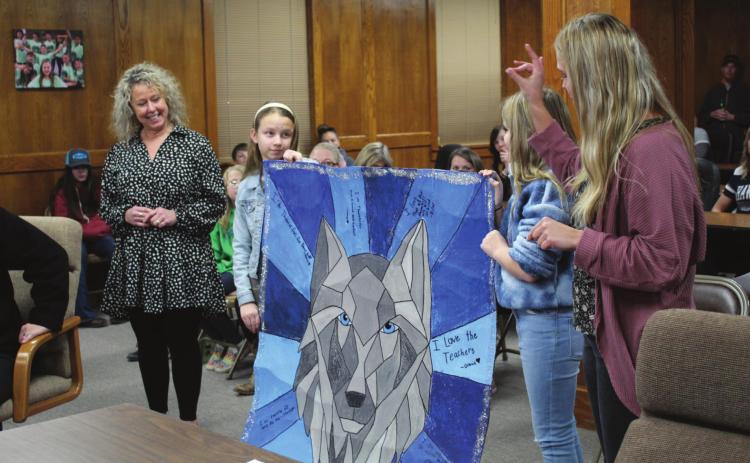 Will Rogers Elementary Principal Jackie Noble, far left, listens as Art Teacher Sidney Smith speaks. Art students Lainey Wilson and Riley Chamblin presented a large, 3D wolf painting, created as a fifth-grade collaboration, to the Shawnee Board of Education on Jan. 10 for School Board Recognition Month. Countywide & Sun/Natasha Dunagan