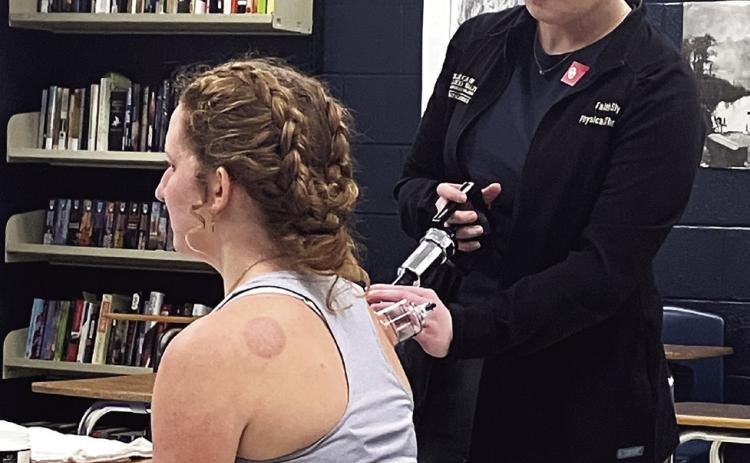 Faith Sly, from Athletico, demonstrates a physical therapy technique called “cupping,” on Tecumseh High School Student Intern, Laycee Thoma, during the carreer fair held at Tecumseh High School on Feb. 25. Adelaide Lack, Intern, Countywide &amp; Sun