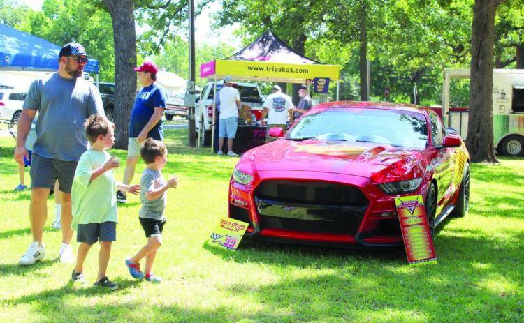 David Garrett, Branley Garrett, 6, and Braylon Garrett, 4, all of Shawnee, look over a “Lightning McQueen” 2016 Ford Mustang GT, owned by Mark Wilson of Edmond at the 37th Annual Knights Auto Club Car Show, June 22, at Briscoe Boy Scout/Rotary Park in Shawnee.