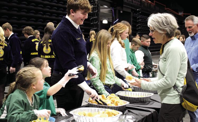 Tecumseh 4-H members Jessi Peacock and Adalyn Seaton and North Rock Creek FFA member Gus Goodson serve Delinda Curtis rolls and butter during the 34th Annual Pottawatomie County Junior Livestock Show Pig Roast and Trophy Auction on Feb. 6. Countywide & Sun/Natasha Dunagan