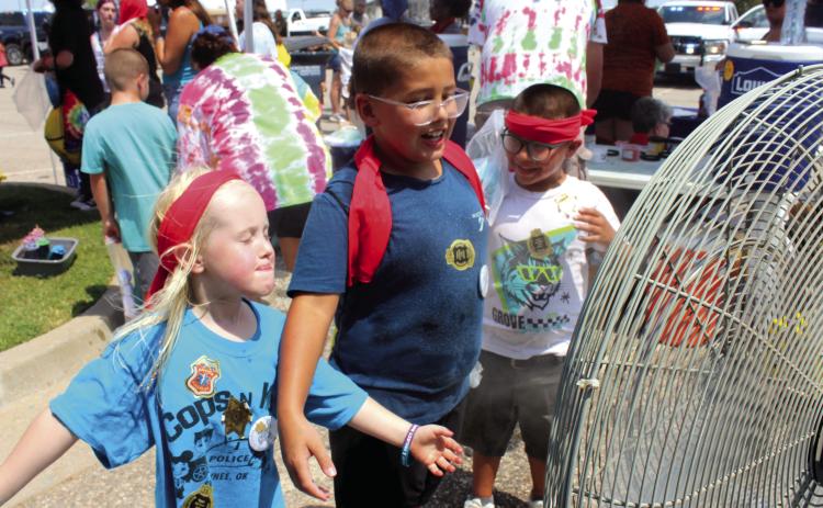 Elinor Peters, 5, Izaiah Peters, 8, and Zaden Peters, 7, all of Shawnee, cool off in front of a misting fan beside the Vision Bank tie-dye tent at Cops N' Kids on Aug. 23. An estimated 2,000 people attended the event at the Heart of Oklahoma Expo Center, said Founder and Coordinator Shawnee Police Cpl. Vivian Lozano-Stafford in an email. It offered more than 30 emergency response agencies and about 25 organization booths.
