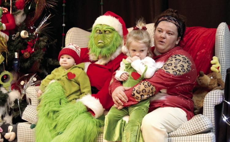 The Grinch poses with Cade Glasgow, six months; Karsin Glasgow, 2; and Ashley Glasgow, all of Tecumseh, during the Grinchmas Whoville event, held in the Tecumseh City Hall Auditorium on Nov. 30, 2023. File photo.
