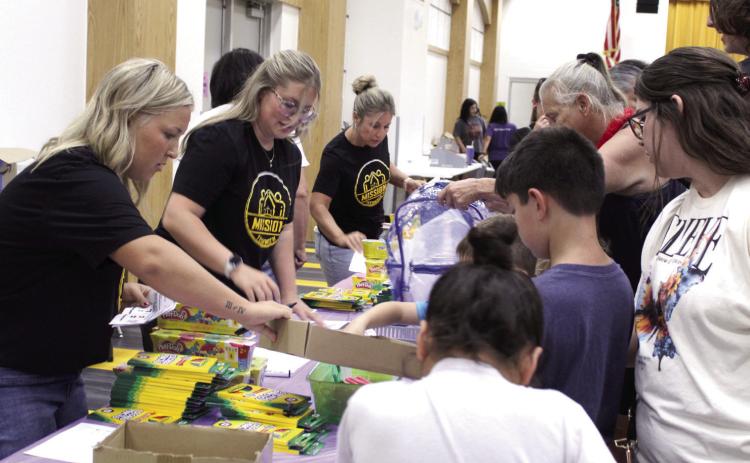 Twins Elise Whitney and Ella (Whitney) Gardner and their mother, Hope Whitney, volunteer at the Mission Tecumseh Back to School Bash, held at the Tecumseh High School W.P. Wood Alumni Center on July 25. Photos by Natasha Dunagan, Countywide & Sun