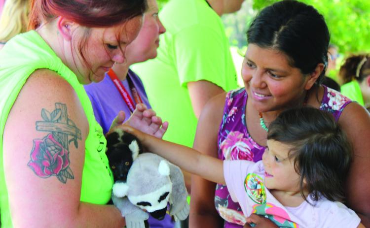 Rhema Brynildsen, 3, is held by her mother, Katrina Brynildsen, both of Tecumseh, as she pets Mort the baby Black-and-White Ruffed Lemur during the Tecumseh Pioneer Library Summer Reading Challenge Extreme Animals program on June 13. This is one of 60 species of lemur found in Madagascar, said handler Keeley Knowles, who also spoke on Burmese pythons, bearded dragons, blue-tongued skinks, European hedgehogs and armadillos. Holding Mort is CPN/CDC After-School Program teacher Kristen Janway.