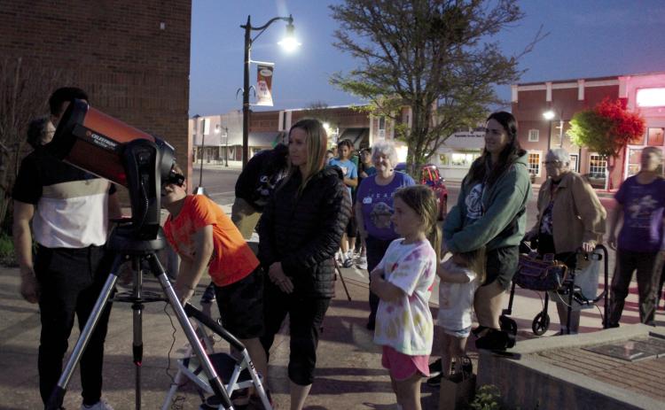 Clancy Humphrey, 6, of Shawnee, looks at Jupiter through a telescope belonging to the Lunar Sooners club from OU, as his mother Bethany Humphrey watches, during a star gazing event at the Tecumseh Public Library on April 5. The Lunar Sooners were represented by graduate students Manuel Barrientos (behind telescope) and Adam Moss, who spoke earlier on the science behind an eclipse and astronomy. Countywide & Sun/ Natasha Dunagan