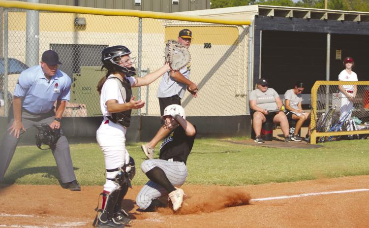 Tecumseh junior Katie Overstreet slides into home as the Holland Hall catcher waits for the throw, and Head Fastpitch Coach Chad Trahan and the umpire watch. Overstreet hit her home run in the second inning of the Aug. 22 game. The Lady Savages won, 11-0. Countywide & Sun/Natasha Dunagan
