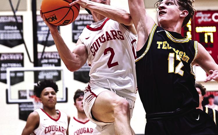 Tecumseh’s Kohen Warden tries to block the shot as North Rock Creek’s David King leaps to the basket. Photo courtesy of Gowin Photography